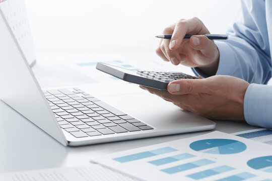 Accounting calculation. Calculating tax with calculator and laptop. Filing and paying taxes.