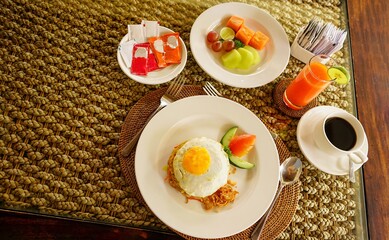 Breakfast at hotel style at Asian style hotel by the swimming pool. Table with delicious food by the beautiful blue pool travel in resort on sunny summer day. Rest and vacation in luxury hotel