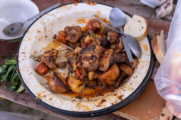 A plate of food is covered in sauce and has a spoon and a piece of bread on it