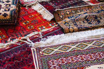 stack of traditional oriental Arab Asian Uzbek handmade colorful carpets at the market in...