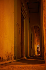 A heritage street house corridor with arches illuminated by neon lights, showcasing a peaceful and calm scene in George Town.