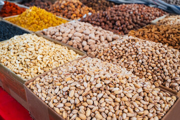 assortment of different variety nuts, dried fruits on counter at oriental Uzbek food bazaar. Almonds, raisins, pistachios, hazelnuts and cashews in market stall