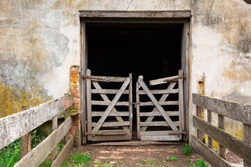 Worn and weathered gates spanning the entrance to an old, dilapidated barn.