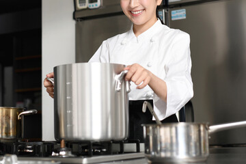 寸胴鍋で調理する若いアジア人の女性調理師