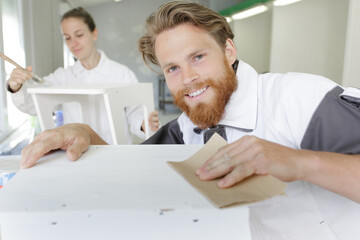 man sanding a wood with sander in a workshop