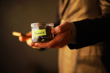 Businessman hand putting money (coin) in the glass jar, vintage tone effect