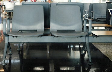 Empty Gray Seats in Modern Airport Terminal. Row of empty gray seats in a modern airport terminal, highlighting the clean and organized public space.