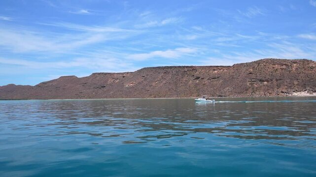 Small boat sailing in Isla Espiritu with desert landscape in the background, Santo, Baja California Sur, Mexico