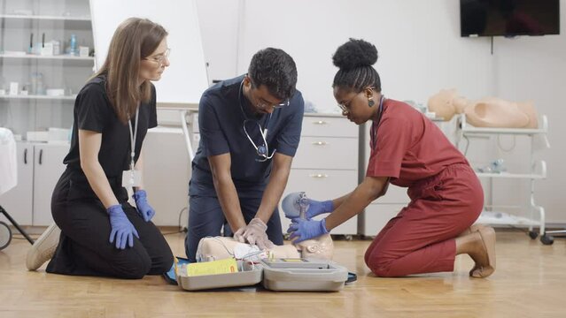 The participants are learning basic first aid procedures, including CPR and the use of a breathing mask