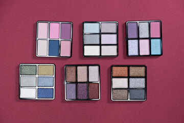 A set of multi-colored eyeshadow on a pink background. Eye makeup