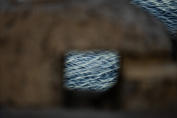 Sea water texture shot through a window hole in an old brick wall.