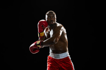 Dynamic image of serious African-American man, boxer with muscular boy, in red gloves and short...