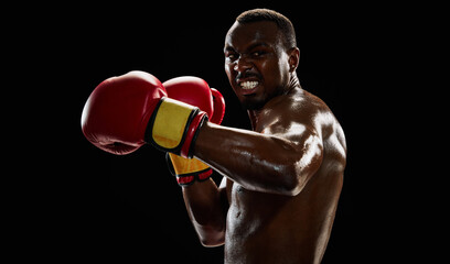 Powerful boxer, African-American in red gloves punching, showcasing strength and focus, training...
