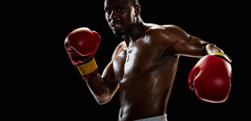 Close-up image of athletic muscular man, African-American boxer showing his perfect physical form...