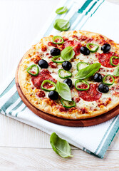 Pizza with salami, jalapeno pepper and black olives. Home made food. Concept for a tasty and hearty meal. Close up.	