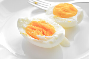 Boiled egg with a fork on a white plate. 