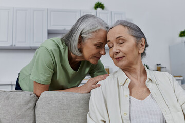 Obraz premium Two mature lesbian women rest on a couch in their modern apartment