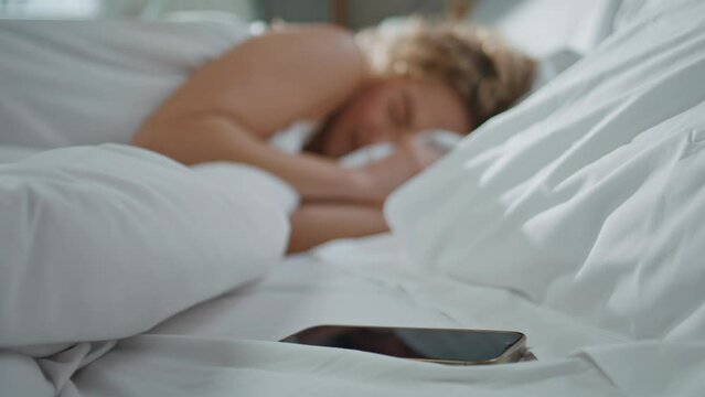 Woman waking cozy bed at home. Closeup hand turning off alarm clock in morning