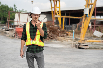 Portrait caucasian engineer man use notebook computer and walkie talkie working at precast cement outdoor factory	