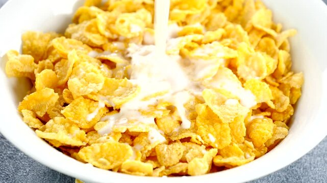 bowl of corn flakes with milk pouring