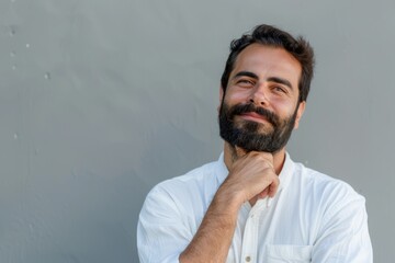 Hispanic man with beard thinking and smiling thoughtfully.