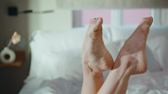 Closeup girl feet sunlight in cozy apartment. Unknown girl rest bed in morning