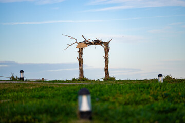 A wooden arch with tree branches for weddings and other events in the middle of a field. Solar lamps in the foreground.