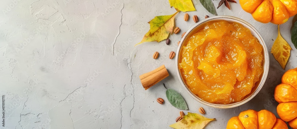 Poster flat lay image of a bowl with scrumptious pumpkin jam and ingredients on tile surface, with room for