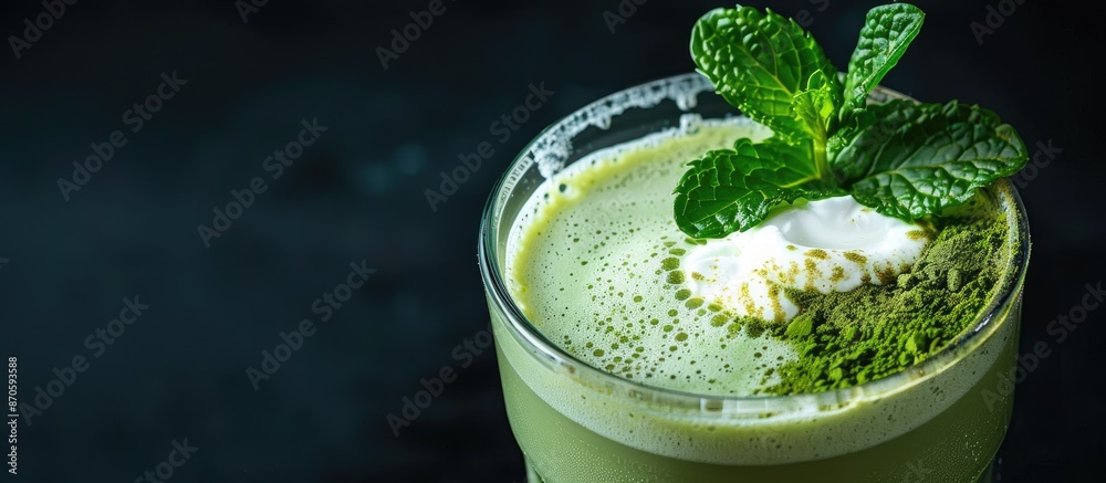 Poster Close-up of a matcha latte and milk foam topped with a mint leaf in a glass on a black background, perfect for text with copy space image.