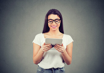 Portrait of a beautiful happy young woman in glasses, using a tablet computer