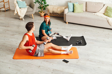 A couple exercises together in a living room. The woman has a prosthetic leg.