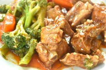 fried pork bone with steamed broccoli and carrot dressing sweet red gravy sauce on plate