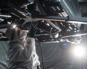 Obraz premium The master sprays an anti-corrosion compound on the bottom of the car. 