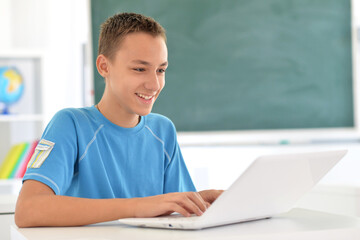 Portrait of boy studing with laptop at classroom