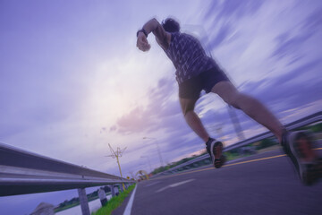 Silhouette of young man running sprinting on road. Fit runner fitness runner during outdoor workout with sunset background with high speed zoom blur effect.