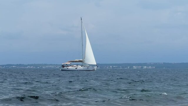 Boat with a sail on the birch water of the Adriatic sea. A white sailboat sails on the blue sea. Sailing holidays off the coast of Croatia, Preko island, June 27, 2024