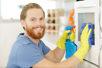 Fototapeta premium man wiping an oven with table cloth