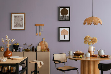 Dinning room and kitchen interior with mock up poster frame, round table, rattan chair, beige commode, vase with dried flowers, cup, pitcher and kitchen accessories. Home decor. Template.
