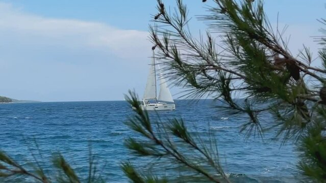 Boat with a sail on the birch water of the Adriatic sea. A white sailboat sails on the blue sea. Sailing holidays off the coast of Croatia, Preko island, June 27, 2024