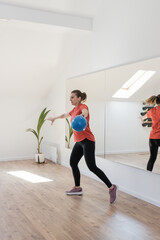 Obraz premium Woman In A Fitness Studio Performing An Exercise With A Blue Ball, Reflected In A Large Mirror 
