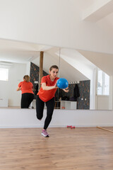 Woman In A Fitness Studio Performing An Exercise With A Blue Ball, Reflected In A Large Mirror	
