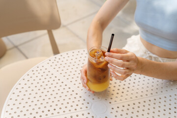 Woman drinking iced bumble coffee. Refreshing drink that combines espresso with orange juice