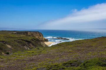 Pacific ocean on sandy Cowell Ranch State beach surrounded by sea cliffs, rocky headlands on summer sunny day in San Mateo County, California