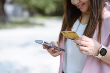 A woman holds a smartphone in one hand and a credit card in the other. Transaction in progress Or they may be checking their accounts.