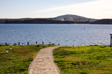 A little paved road pathway on an island in the sea. The shore can be seen in the background. 