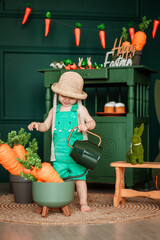 little girl in green overalls watering decorative carrots