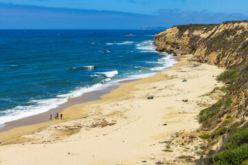 Pacific ocean on sandy Cowell Ranch State beach surrounded by sea cliffs, rocky headlands on summer sunny day in San Mateo County, California