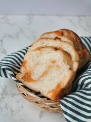 a hand holding several slices of white bread above a round wooden cutting board. The bread, evenly sliced and slightly fanned out, looks fresh and soft. Below the hand