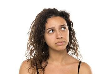 Portrait of a young pensive woman without makeup on a white background