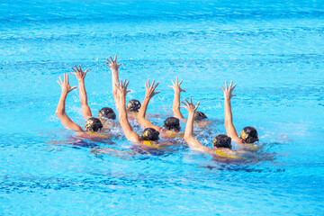 Artistic swimming team performing synchronized choreographed routine in the swimming pool